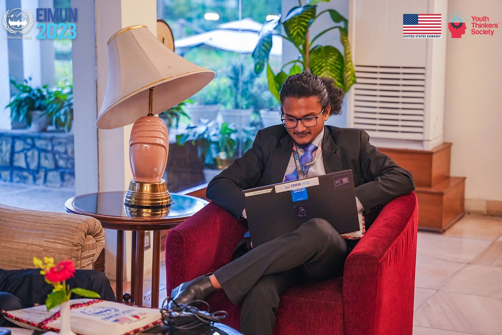 Hikmat working on a laptop in a red armchair