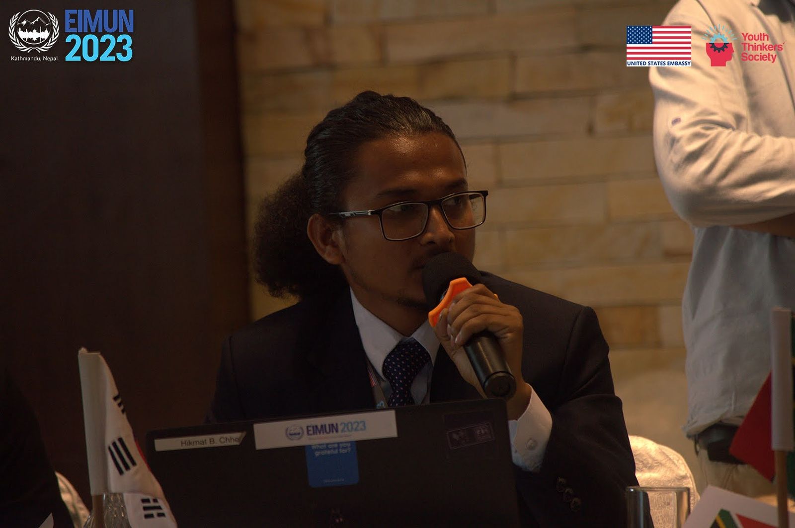 Hikmat speaking into a microphone in committee session