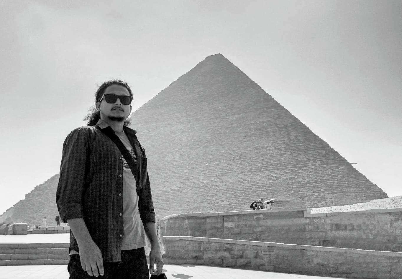 Black-and-white photo of Hikmat in sunglasses in front of the Great Pyramid