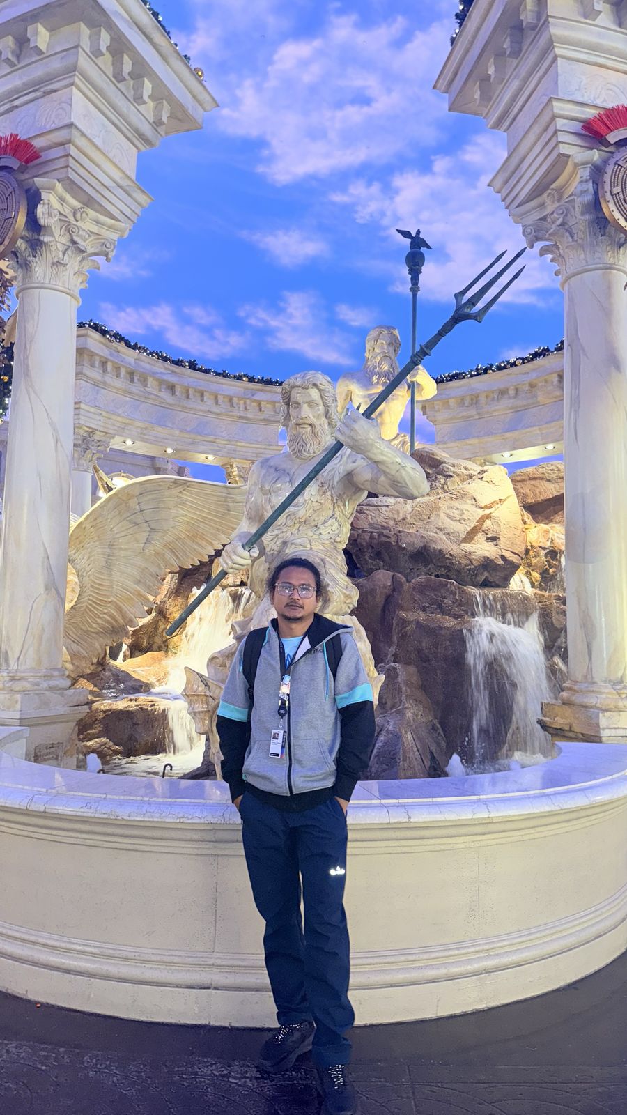 Hikmat standing in front of a fountain with classical statues